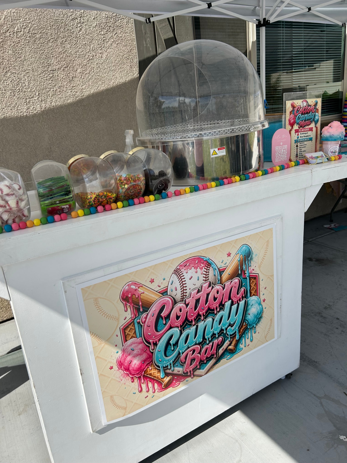 Baseball-themed cotton candy bar setup with custom signage and toppings