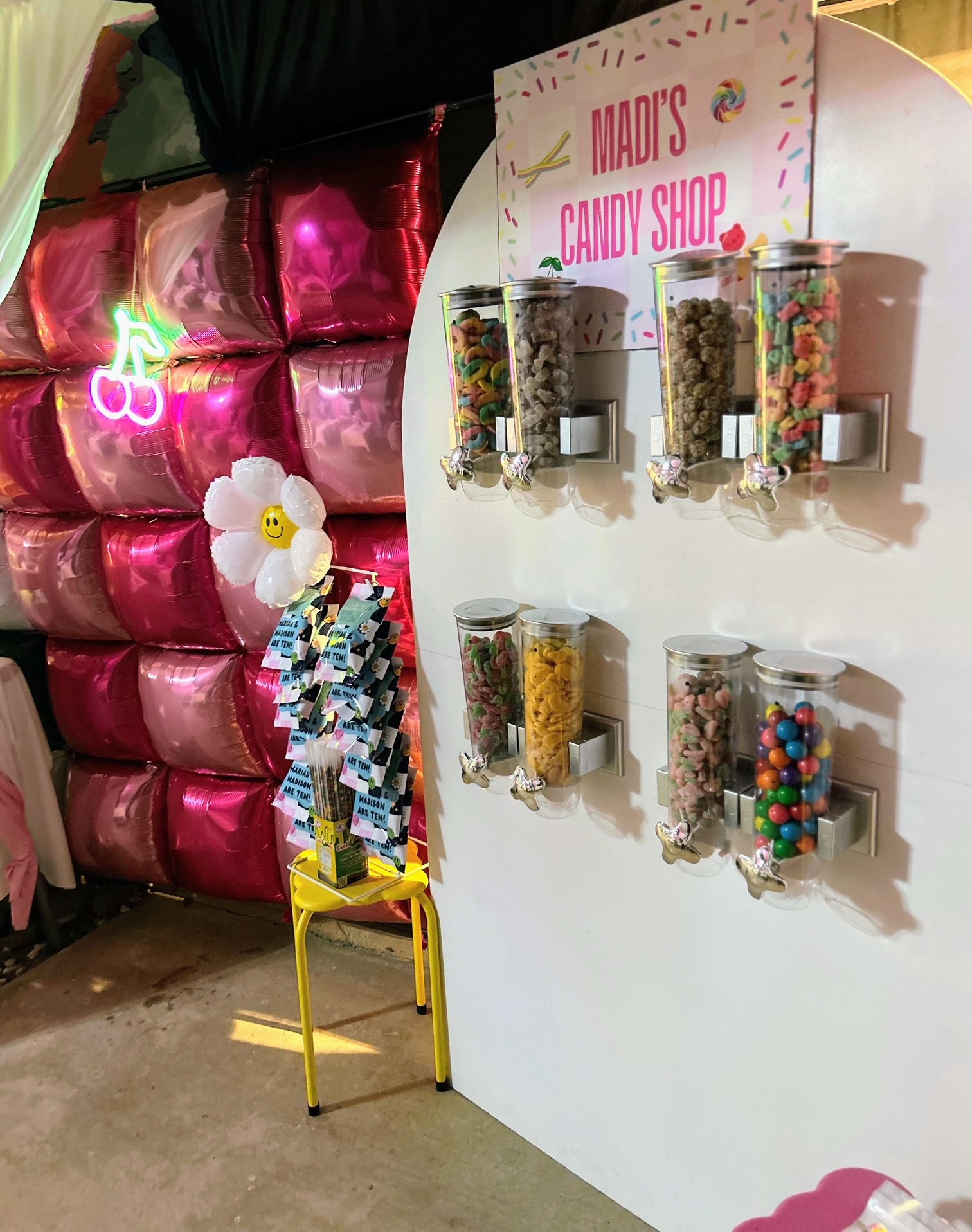 Custom candy shop wall with colorful dispensers and personalized signage at an event