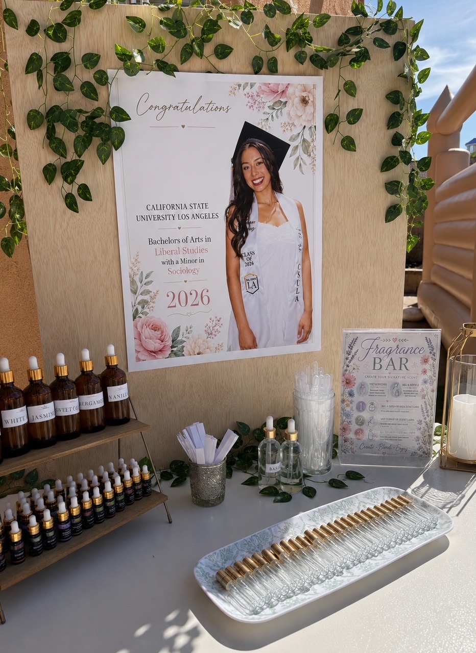 Elegant fragrance bar setup with perfume bottles, custom signage, and greenery backdrop