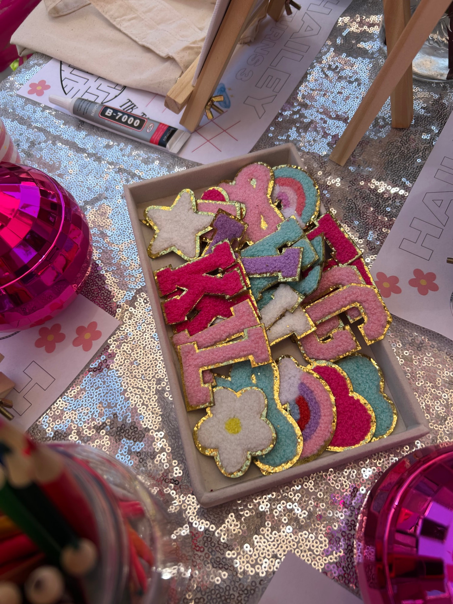 Tray of colorful embroidered patches with gold outlines, rainbows, stars, hearts, and flowers for accessory styling