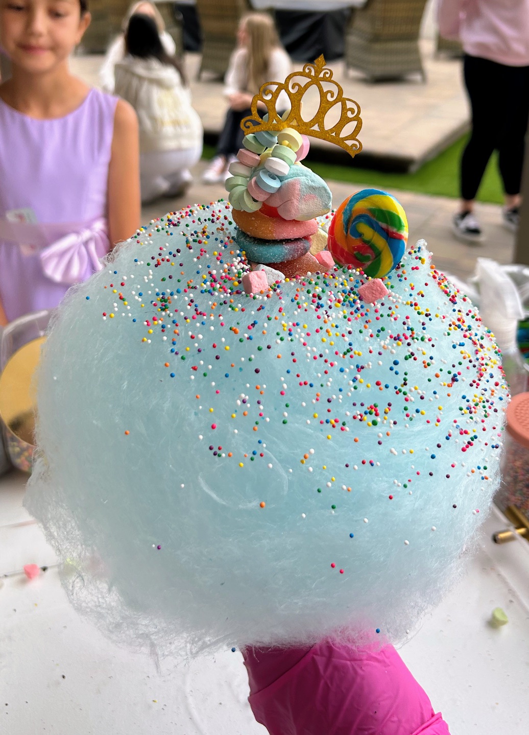 Giant blue cotton candy topped with sprinkles, candy, and a golden crown